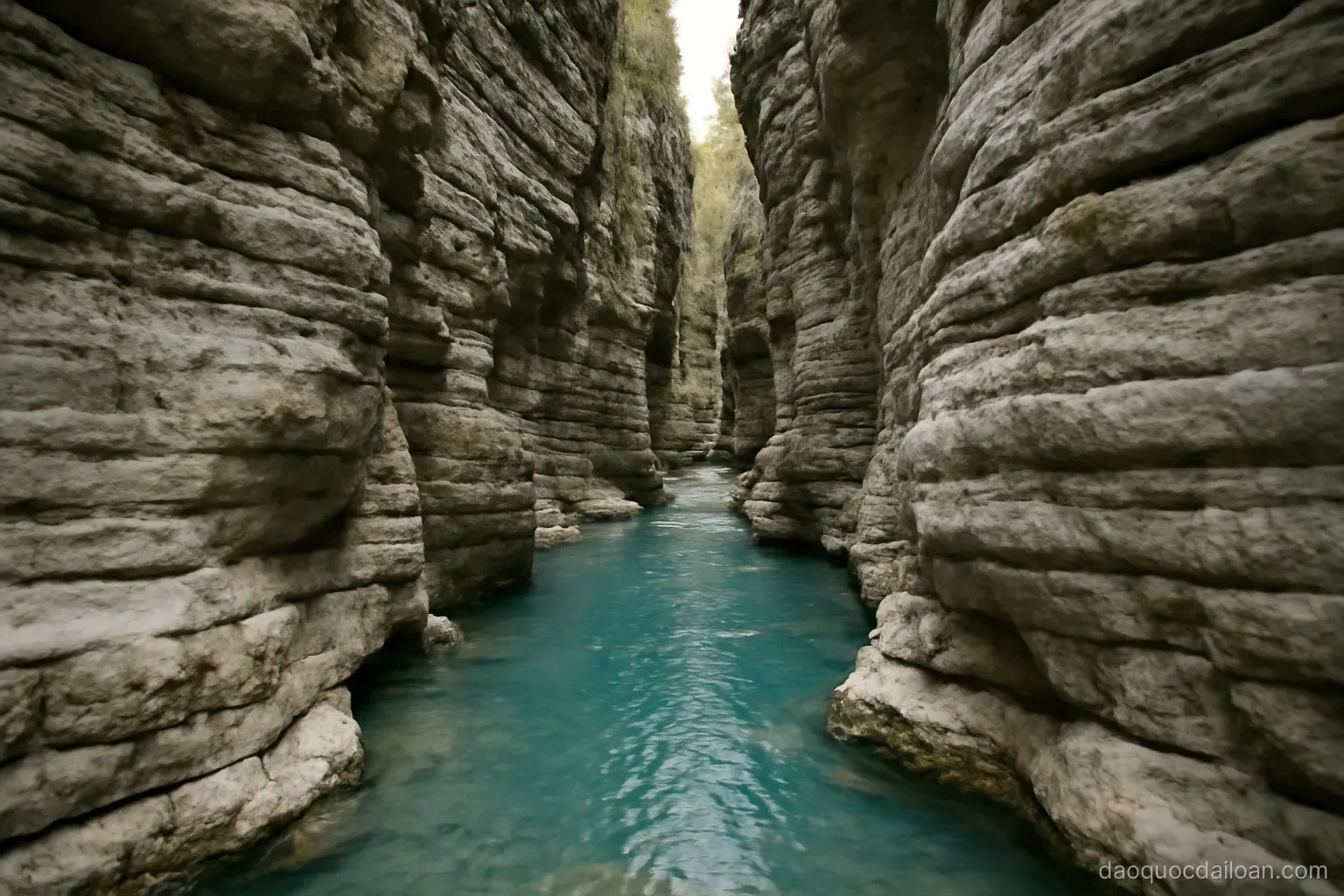 A narrow gorge with pale grey striped rock walls rising on both sides above a turquoise river, no readable text
